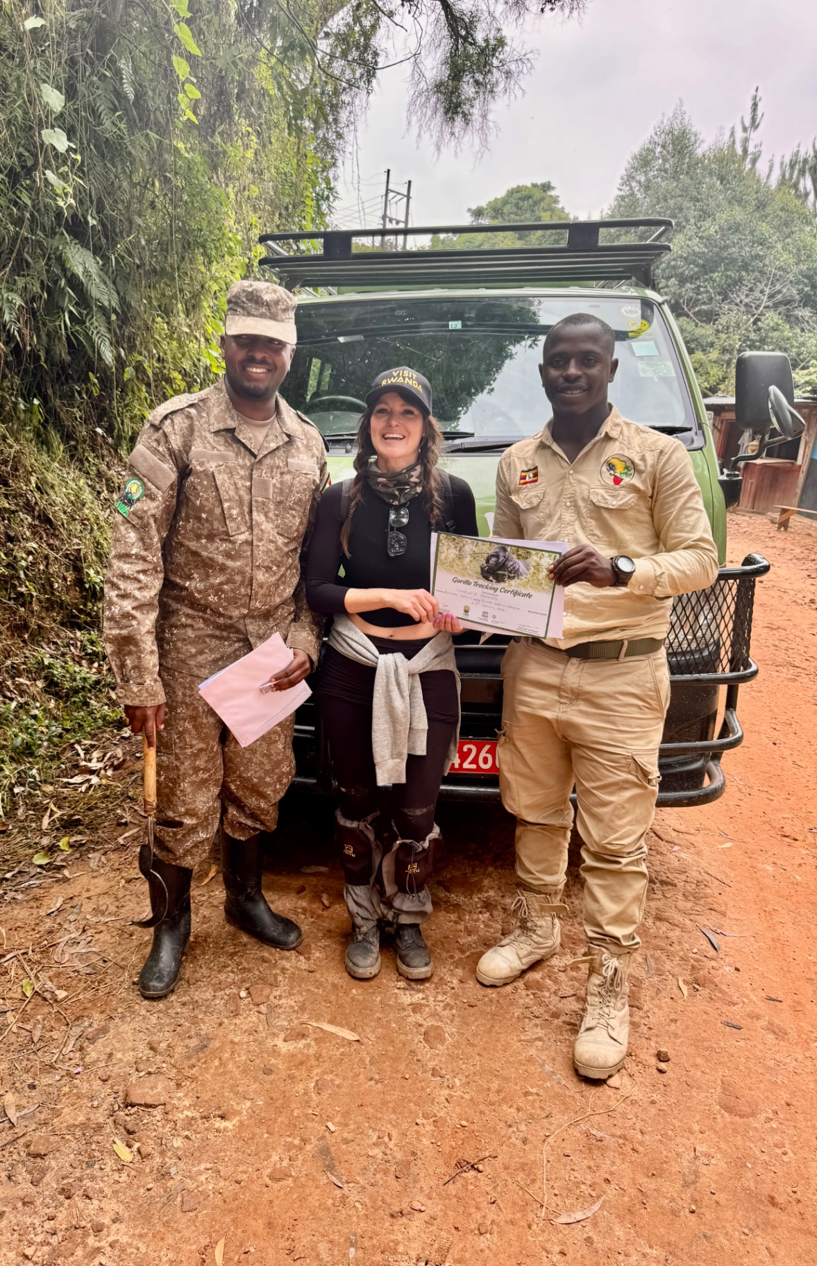 Charlotte Z. with a Rwandan park ranger and Ugandan guide holding a gorilla tracking certificate